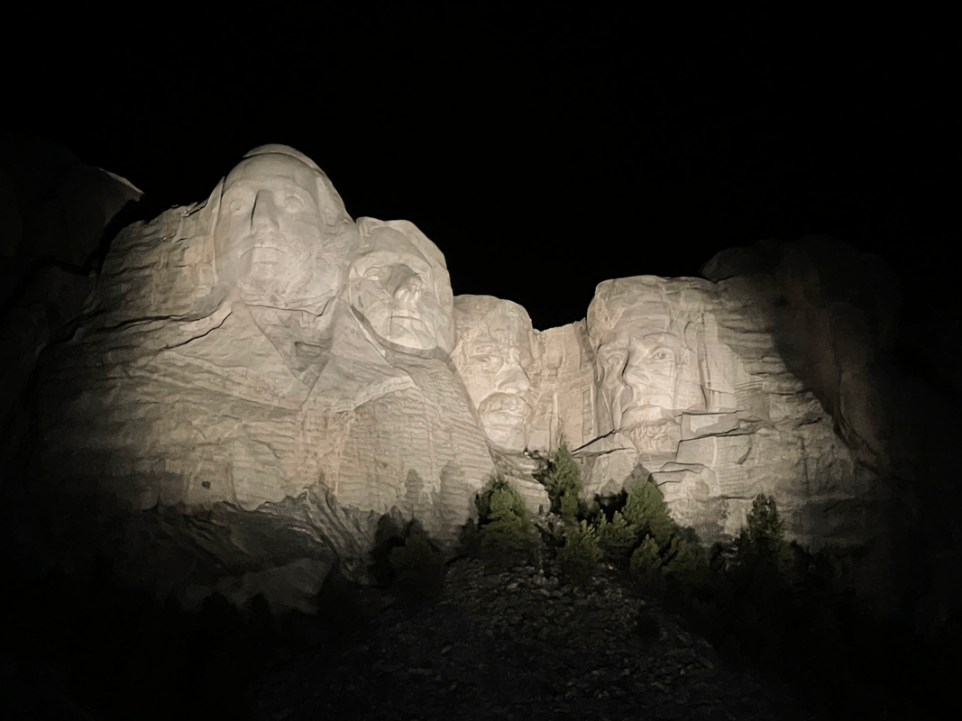 mount rushmore illuminated at night with all four presidents