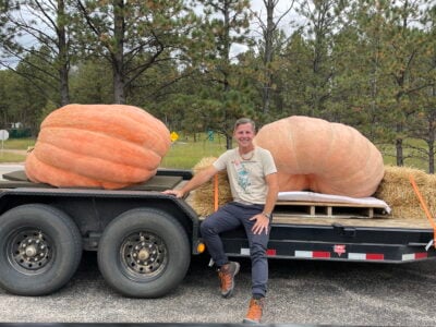 daniel sitting on a trailer with giant pumkins employment with my xo adventures