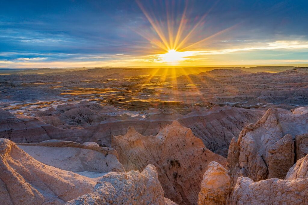Sunrise To Sunset In The Badlands 5 sunrise over the badlands in south dakota, with golden rays illuminating layered rock formations against a lavender sky.