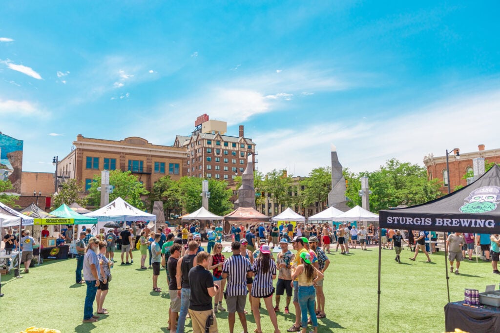 Dining And Shopping In The Black Hills: A Culinary &Amp; Retail Adventure 11 outdoor summer craft beer festival in rapid city’s downtown plaza with white vendor tents, green turf and people sampling brews under a clear blue sky