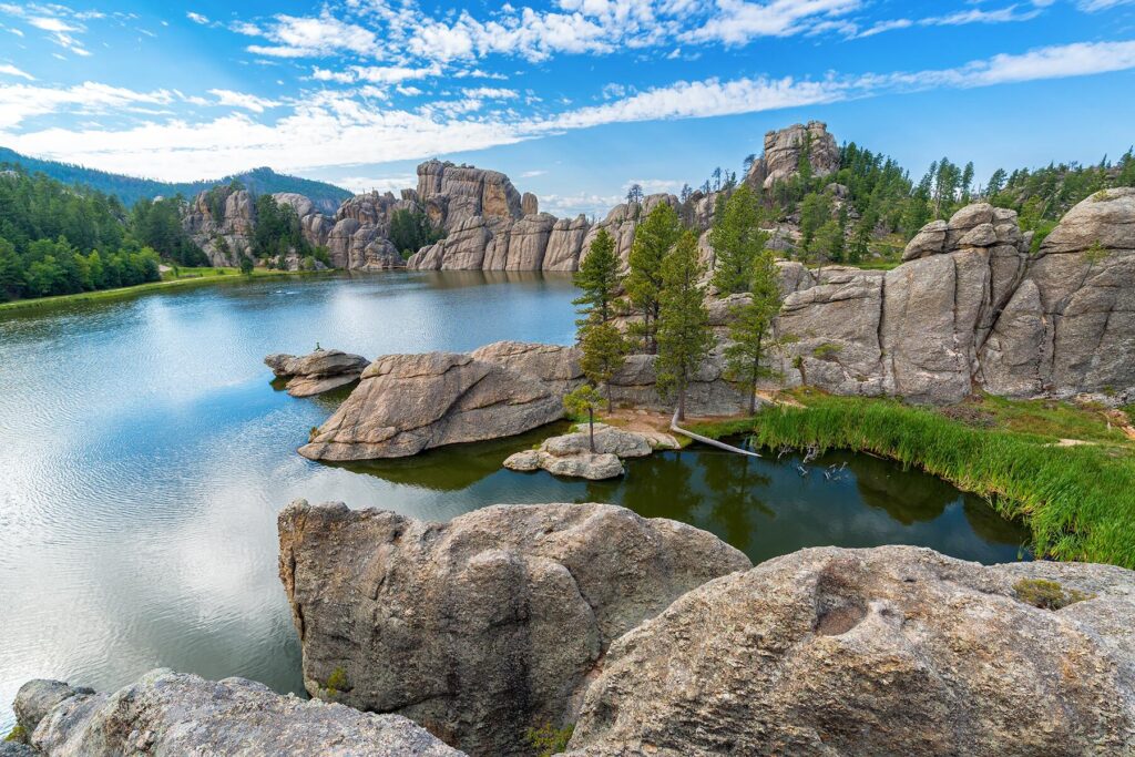 The Ultimate Guide To A Family Vacation In The Black Hills, South Dakota 8 tranquil sylvan lake in the black hills framed by granite boulders and evergreen pines, reflecting a bright sky. a perfect family adventure setting.